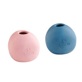 Der Beco Wobble Ball aus Naturkautschuk liegt befüllt mit Leckerlis auf dem Boden, während ein neugieriger Hund versucht, ihn durch Anstupsen und Rollen zu bewegen.