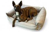 Hund schläft bequem auf einem nachhaltigen Hundebett mit abnehmbarem und waschbarem Bezug, das aus recyceltem Textil gefertigt wurde.